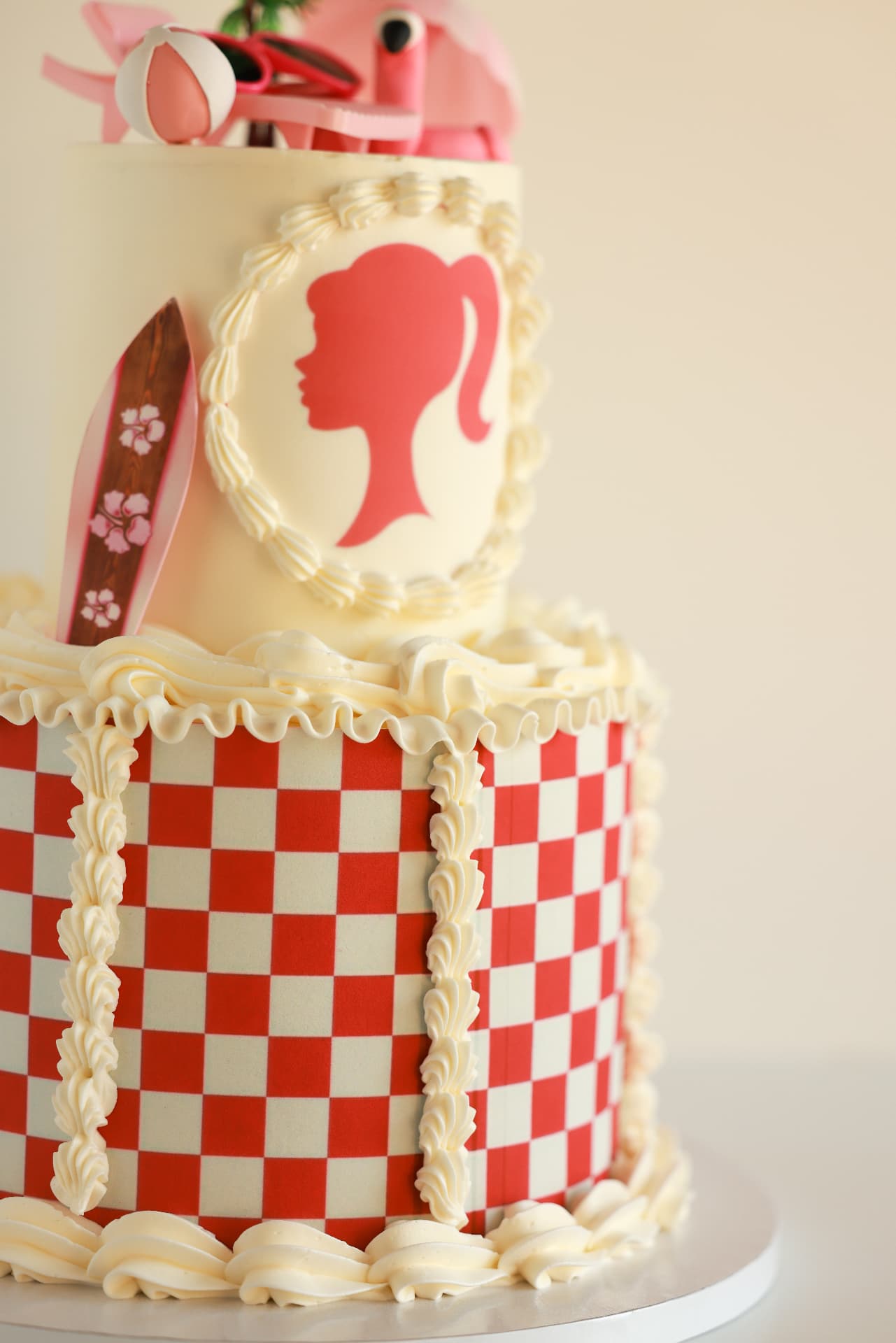 Custom two-tier cake with red checkerboard icing and a pink silhouette detail